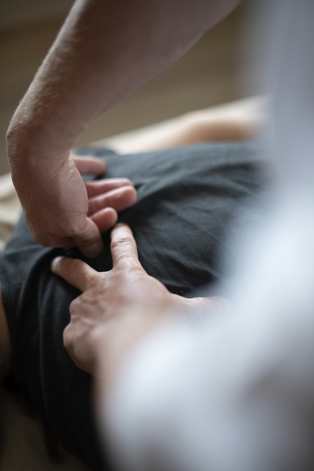Close das mãos do fisioterapeuta aplicando técnica manual na região lombar de um paciente